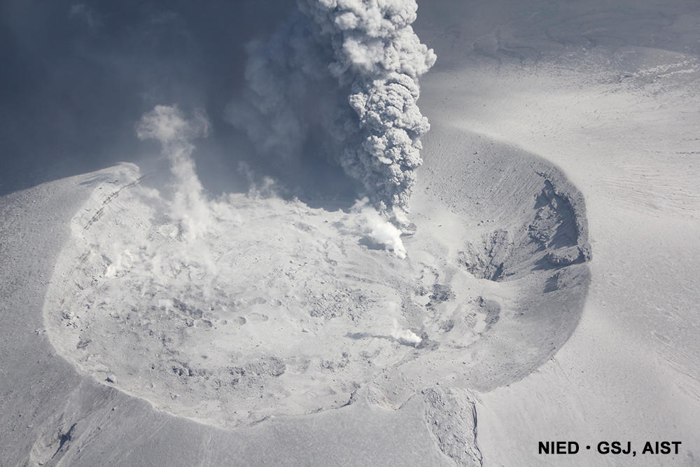 新燃岳火口から上がる火山灰混じりの噴煙。灰色噴煙の手前に水たまりがある。（2017年10月12日10時50分頃）